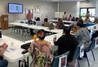 People sitting around white tables listening to a presentation